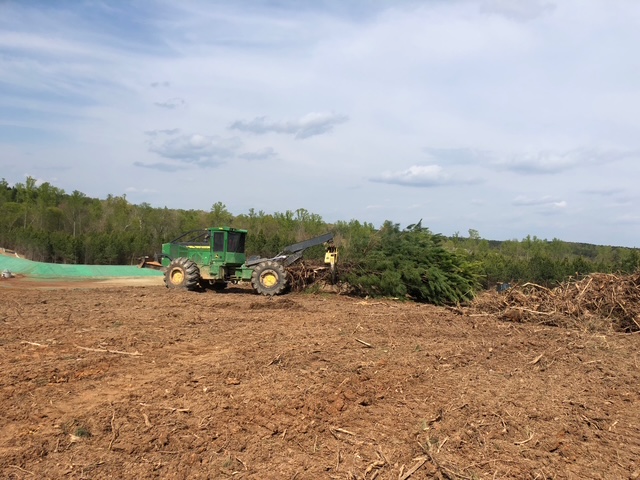 John Deere skidder moving cleared timber into a debris pile