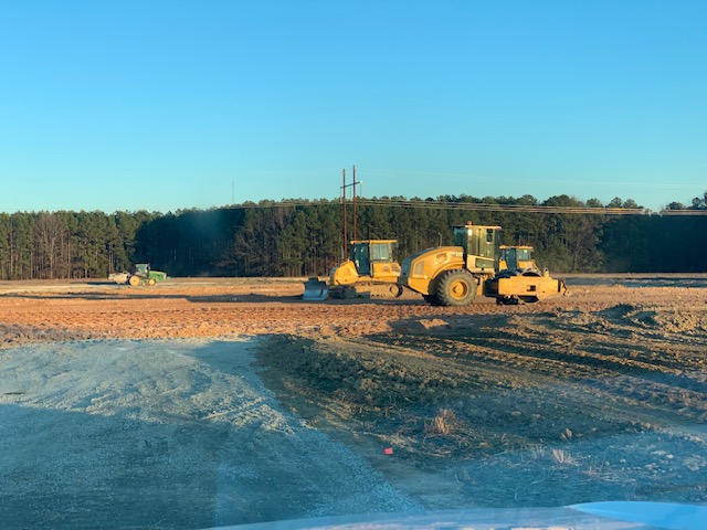 Motor grader and roller shaping subgrade at sunrise