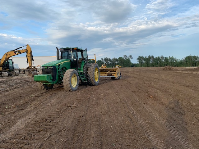 Tractor with pulverizer and excavator preparing subgrade on a graded pad
