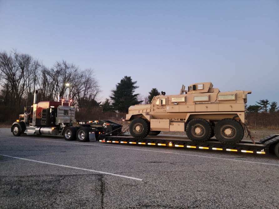 Lowboy trailer hauling an armored vehicle for HGS Contracting